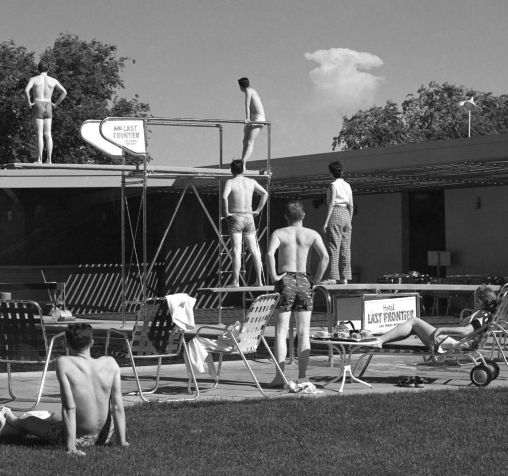 Les baigneurs tôt le matin à la piscine d'un hôtel à Las Vegas s'arrêtent pour regarder le nuage de champignons d'une détonation atomique sur un site d'essai à environ 75 miles de la ville. 8 mai 1953.